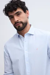 Camisa de manga larga fit semi slim color celeste, con cierre frontal de botones y cuello camisero clásico.