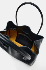 Bolso tipo shopper de cuero sintético en color azul oscuro, con diseño fruncido, doble asa de mano y cordones ajustables a los lados.