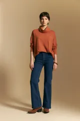 Polera de tejido de punto color naranja con cuello alto de caída relajada y diseño de líneas en relieve. Presenta una silueta holgada con hombros caídos y mangas largas.