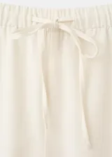 Pantalón palazzo color blanco con detalles bordados en el bajo de las piernas, tiro medio y cintura elástica con cordón ajustable.