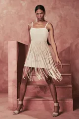 Vestido corto color beige con breteles finos y falda con flecos.