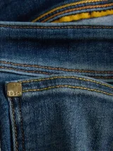 Bermuda de jean azul con efecto gastado y dobladillo revuelto en las piernas, de corte clásico.