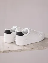 Championes negros de cuero sintético con suela blanca de goma.