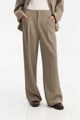 Pantalón de vestir de corte ancho y tiro alto, color verde oliva o gris topo, con pliegues frontales marcados.