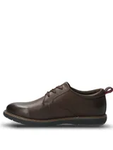 Zapato casual Hush Puppies modelo Bolo, confeccionado en cuero color marrón oscuro. Presenta cierre con cordones, suela de EVA flexible y diseño estilizado con costuras visibles en el borde de la suela.