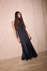 Vestido largo de seda color negro con estampado de lunares blancos. Presenta una silueta fluida, escote en V profundo con detalles de encaje y espalda descubierta con tiras cruzadas.