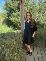 Vestido corto negro de lino, con cuello mao, escote de dos botones de nácar, mangas con volados y ruedo inferior con volado.