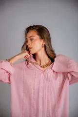 Camisa rosada con detalles de broderie en la parte delantera y mangas anchas.