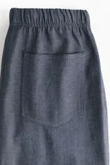 Pantalón recto de corte holgado con cintura elástica de tiro alto y cordón ajustable. Presenta bolsillos delanteros y traseros abiertos.