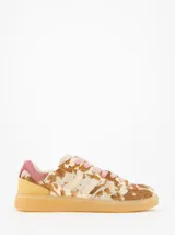 Championes de estilo urbano con estampado animal print tipo vaca en tonos marrones y beige. Presenta detalles en gamuza rosada en el talón, cordones rosados y suela de goma color caramelo.