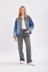 Campera de jean con diseño bicolor, combinando paneles en color gris oscuro y azul denim. Presenta cuello camisero, cierre frontal con botones metálicos y corte holgado.