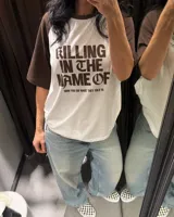 Remera estilo raglan con cuerpo blanco y mangas cortas marrones, con diseño gráfico inspirado en Rage Against The Machine y la frase 'Killing In The Name Of' en el frente.