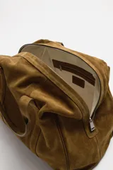 Bolso de mano marrón de cuero con acabado serraje. Tiene un compartimento principal con cierre de cremallera, dos bolsillos interiores (uno con cremallera) y asas de mano de cuero.