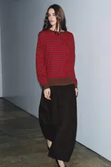 Jersey de punto con diseño a rayas horizontales en color rojo y marrón. Presenta cuello redondo, manga larga con puños ajustados y ruedo acanalado.