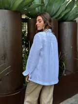 Chaqueta azul de manga larga con cuello camisero, cierre con botones y bolsillos frontales.
