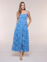Vestido midi color azul con bordado broderie floral en tono blanco, escote recto con tirantes finos de lazo para anudar, corte ajustado en la cintura y falda escalonada holgada con bolsillos laterales.