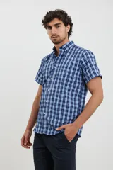 Camisa de manga corta con cuello abotonado y estampado a cuadros en tonos azul y celeste.