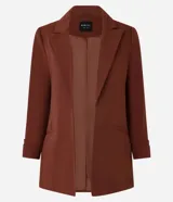 Blazer de sastrería color bordó, de corte oversized y largo, confeccionado en crepé. Presenta solapas clásicas, bolsillos frontales y detalle de pliegues en los puños.