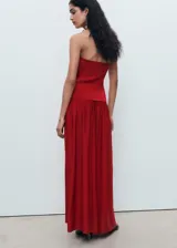 Vestido largo rojo de punto combinado, con cuello halter, sin mangas y diseño evasé con falda fluida y amplia.