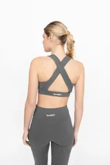 Top deportivo gris con espalda cruzada y compresión alta.