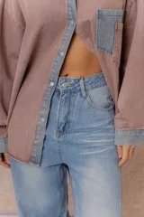 Jean de tiro alto con silueta balloon oversize, confeccionado en denim rígido de lavado celeste desgastado. Presenta costuras curvas que aportan volumen, cierre y botón frontal, y bolsillos funcionales.