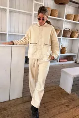 Pantalón casual beige de corte recto, con bolsillos laterales y pespuntes en contraste.