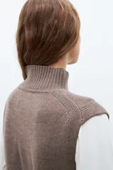 Vestido midi tejido color chocolate, de corte recto, cuello alto y sin mangas. Presenta un tajo frontal.