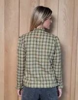 Camisa de manga larga con estampado de rayas verticales en tonos blanco y lila. Presenta cuello alto con volados, cierre frontal con doble botonadura y puños con volados.