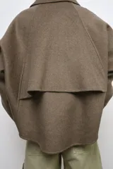Cazadora negra con lana ZW Collection, cuello solapa, manga larga y cierre frontal con cremallera metálica. Cuenta con detalles de tejido tipo capa en la espalda y bajo asimétrico.
