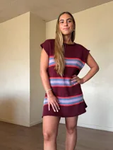 Vestido corto de punto de algodón color bordó, con diseño de rayas horizontales en tonos celestes y rojos, silueta recta y cuello redondo sin mangas.