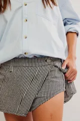 Falda pantalón corta con estampado de cuadros vichy en blanco y negro, diseño cruzado al frente y short interno.