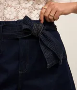 Short tipo mom de jean azul marino con cintura alta, bolsillos delanteros y cinturón ajustable confeccionado en la misma tela con pespuntes visibles.