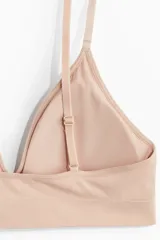 Soutien de diseño minimalista confeccionado en tejido suave sin costuras, con escote en V profundo, breteles ajustables y copas con relleno extraíble.