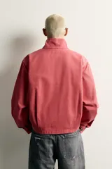 Cazadora relaxed fit de algodón lavado color bordó, con cuello subido y cierre frontal de cremallera de doble dirección. Cuenta con bolsillos ocultos en las costuras de la cadera y mangas largas con puños abotonados.