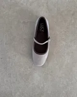 Ballerinas estilo Mary Jane marca Lucy in the Sky, confeccionadas en terciopelo color beige con ribetes y forro interior en color marrón oscuro. Presentan una tira ajustable con hebilla metálica sobre el empeine.