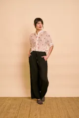 Pantalón negro de corte holgado y pernera ancha, con cintura elástica ajustable mediante cordón y detalles de encaje lateral.