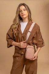 Bandolera compacta color rojo con textura de cuero, correa regulable y desmontable con diseño de rayas rojas y blancas. Cuenta con bolsillos frontales y cierre, interior forrado en tela.