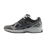 Championes New Balance modelo 1906R, de diseño técnico y deportivo en tonos gris, blanco y plateado, con detalles en verde lima. Presenta una estructura de malla transpirable con refuerzos sintéticos y entresuela amortiguada.