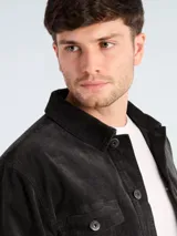 Campera de pana color gris oscuro, con cierre frontal de botones, cuello clásico y bolsillos frontales con solapa y botón.