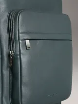 Mochila Calvin Klein color verde oscuro, de cuero sintético con textura micro pebble. Tiene un bolsillo frontal con cierre, asa de mano y correas acolchadas ajustables. Interior con funda acolchada para laptop, bolsillo con cierre y portabolígrafos.