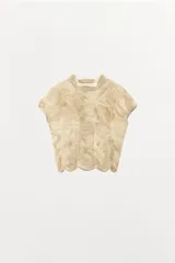 Top de punto con mezcla de viscosa, color beige, con cuello subido y manga corta. Presenta un diseño con frunces verticales y detalles bordados a tono, con terminación de ruedo ondulado.