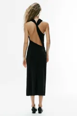 Vestido midi negro de cuello halter con efecto cruzado, espalda con abertura asimétrica y frunces drapeados en el delantero.
