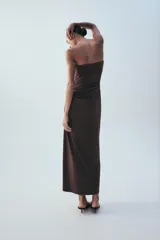 Vestido midi de escote recto sin tirantes, color marrón, con diseño semitransparente en la sección del abdomen y detalle drapeado en la falda. Cuenta con cierre lateral.