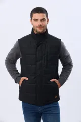 Chaleco reversible capitoneado de corte estándar, con cuello alto, cierre frontal de cremallera y botones a presión. Cuenta con bolsillos laterales y un bolsillo vertical en el pecho.