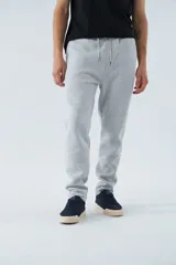 Pantalón de jogging gris melange, de corte recto y ajuste holgado. Cuenta con cintura elástica con cordón ajustable, bolsillos laterales y logo estampado en una de las piernas.