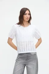 Blusa blanca de tela broderie con mangas cortas abullonadas, cuello redondo y calce clásico.