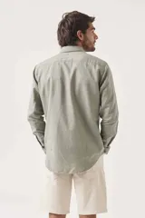 Camisa de lino color verde claro, de corte recto, con cuello abotonado y mangas largas.