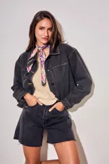 Campera oversize de denim negro, con cuello camisero, cierre frontal con botones y bolsillos ojal.