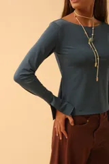 Remera de manga larga con cuello bote, confeccionada en tejido de algodón. Presenta un corte recto y aberturas laterales en los puños.