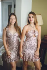 Vestido corto negro con estampado de plumas doradas, escote en V, breteles finos cruzados en la espalda, cut-outs laterales y volado en el ruedo.